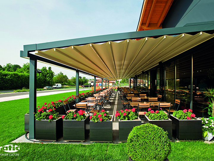 cream retractable awning that is opened entirely over a long dining area outside